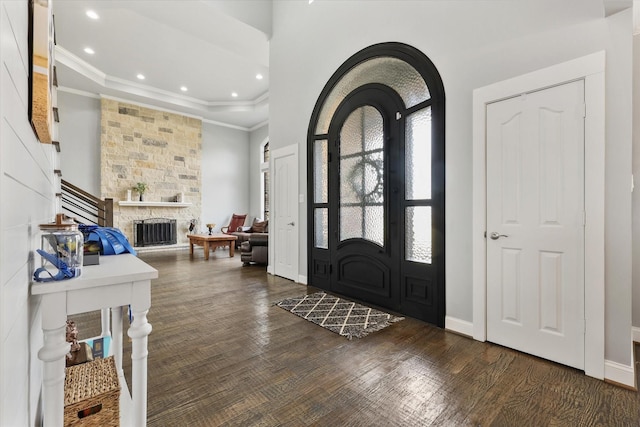 entrance foyer featuring dark hardwood / wood-style floors, a stone fireplace, and ornamental molding