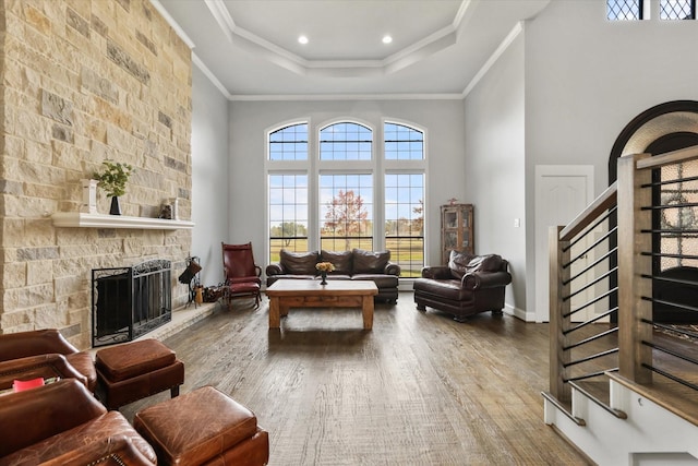 living room with hardwood / wood-style floors, ornamental molding, a fireplace, and a high ceiling