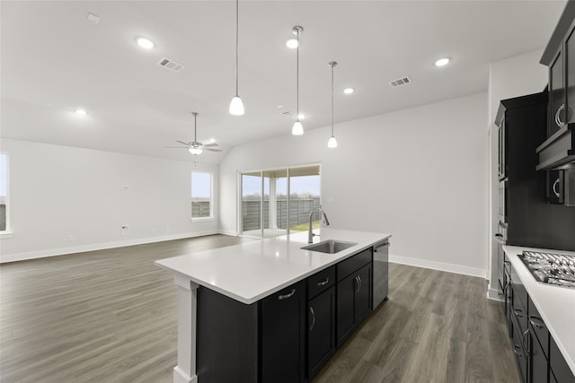 kitchen featuring dark hardwood / wood-style floors, sink, hanging light fixtures, stainless steel appliances, and a center island with sink