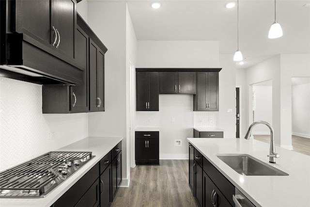 kitchen with sink, wood-type flooring, decorative light fixtures, stainless steel gas stovetop, and decorative backsplash