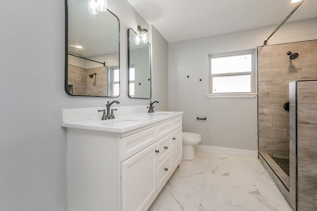 bathroom with a tile shower, vanity, and toilet