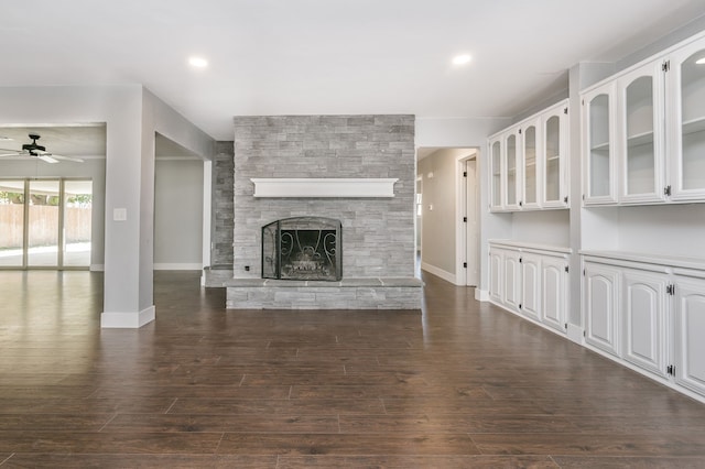 unfurnished living room featuring dark wood-type flooring, ceiling fan, and a fireplace