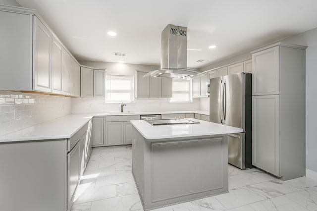 kitchen featuring stovetop, sink, stainless steel fridge, island exhaust hood, and a center island