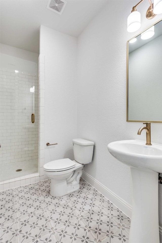 bathroom with visible vents, toilet, a stall shower, a sink, and baseboards