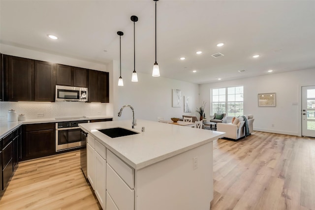 kitchen featuring a center island with sink, light wood-type flooring, sink, and appliances with stainless steel finishes