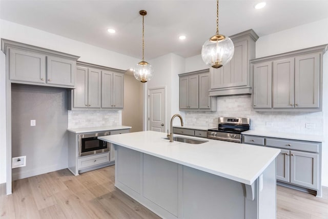 kitchen featuring electric stove, light countertops, hanging light fixtures, a sink, and built in microwave