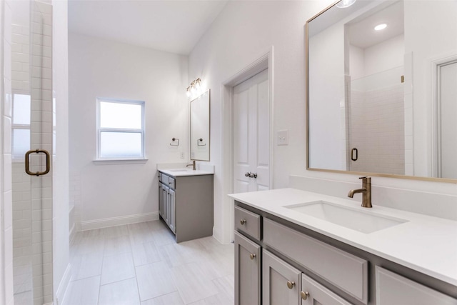 full bathroom with a stall shower, baseboards, two vanities, and a sink