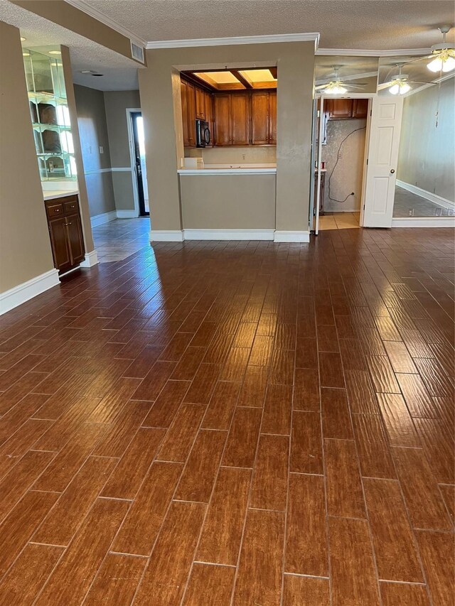 unfurnished living room with dark hardwood / wood-style floors, ceiling fan, ornamental molding, and a textured ceiling