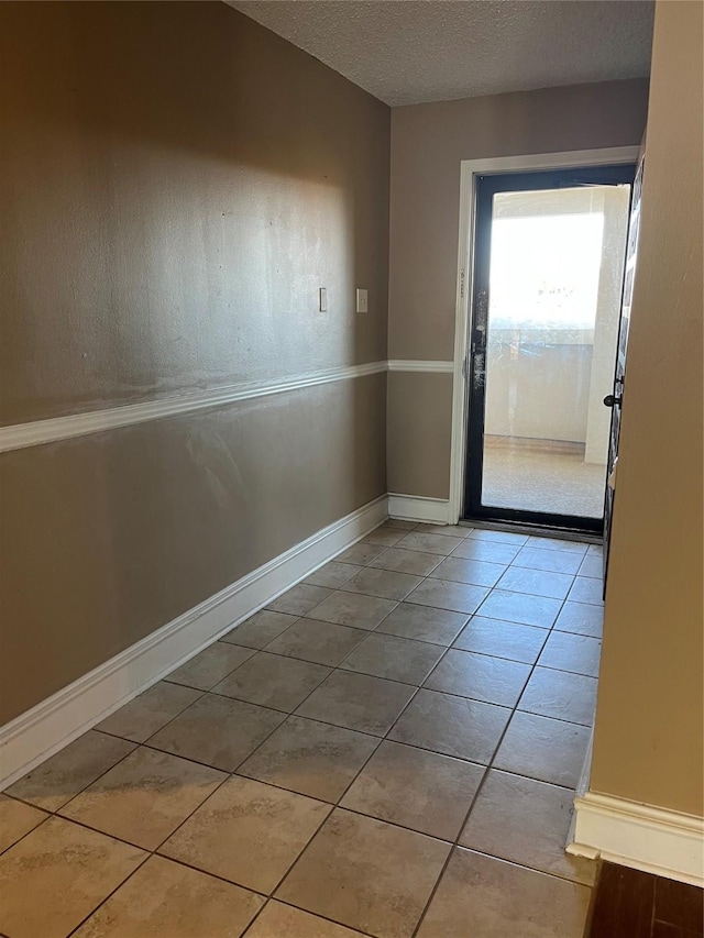 doorway with light tile patterned floors and a textured ceiling