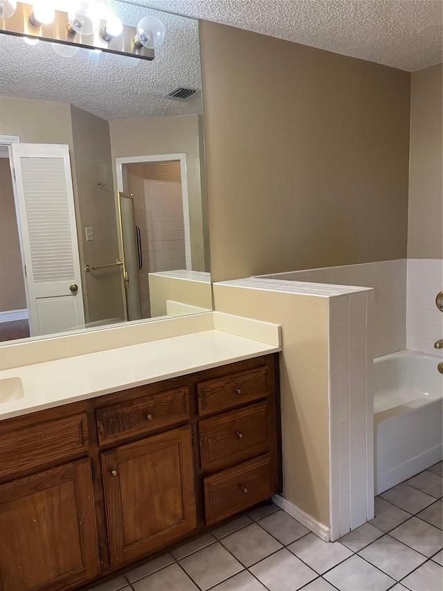 bathroom with tile patterned floors, vanity, shower with separate bathtub, and a textured ceiling