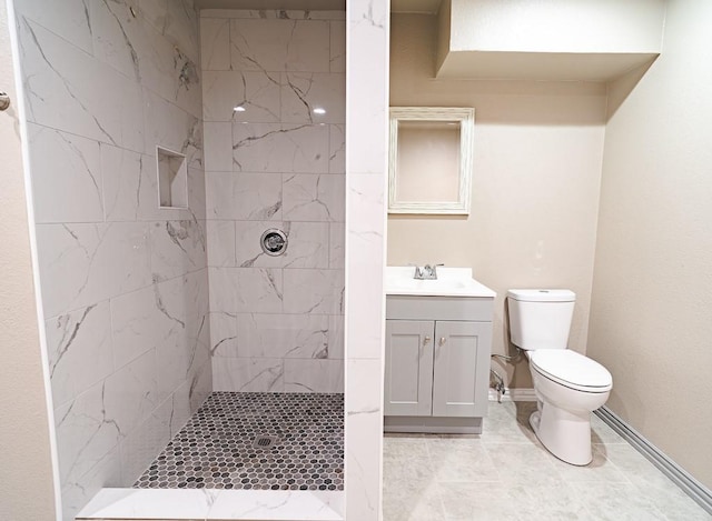 bathroom with tile patterned flooring, vanity, toilet, and tiled shower