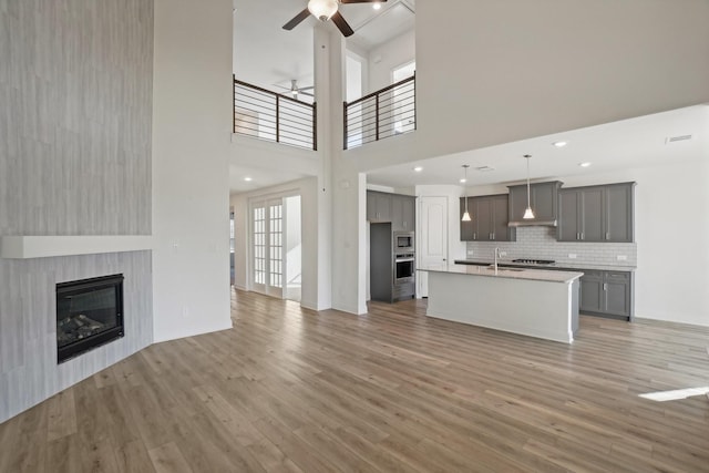 unfurnished living room with ceiling fan, hardwood / wood-style floors, and a high ceiling