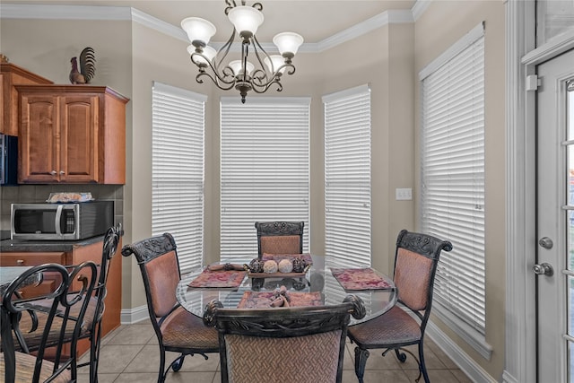 tiled dining area with a chandelier, plenty of natural light, and crown molding