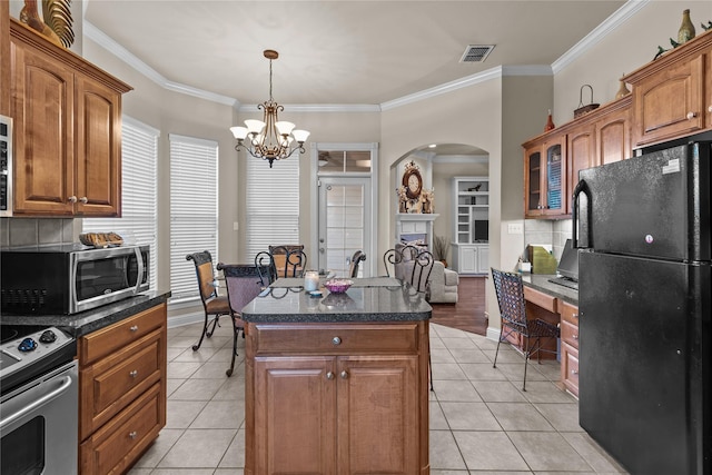 kitchen with appliances with stainless steel finishes, ornamental molding, pendant lighting, a notable chandelier, and a kitchen island