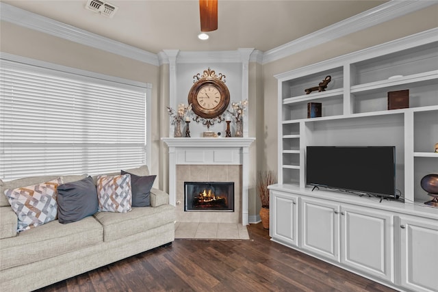 living room with a tile fireplace, dark hardwood / wood-style flooring, ceiling fan, and crown molding