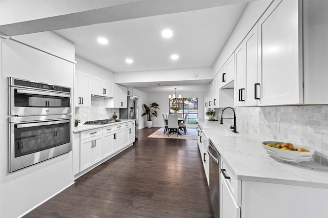 kitchen with white cabinetry, appliances with stainless steel finishes, dark hardwood / wood-style floors, and light stone counters