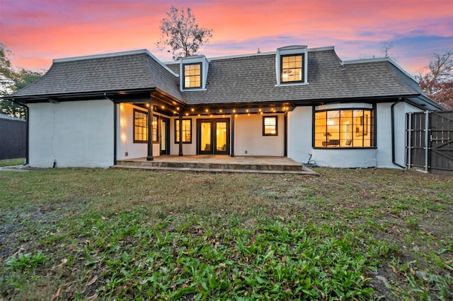 back house at dusk with a lawn and a patio