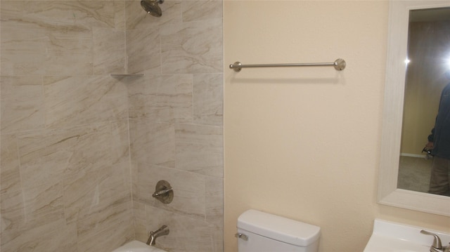 bathroom featuring tiled shower / bath combo and toilet