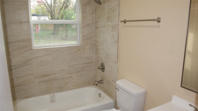 bathroom featuring tiled shower / bath combo and toilet