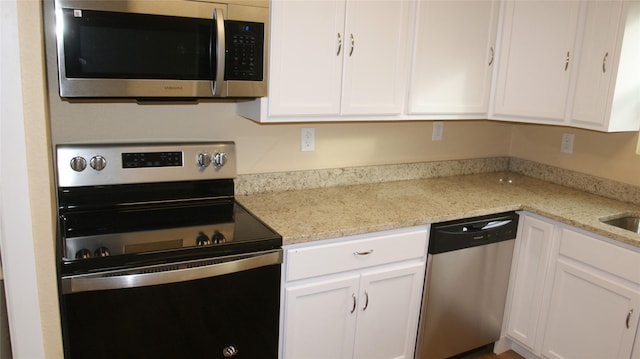 kitchen with white cabinetry, light stone counters, and appliances with stainless steel finishes