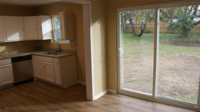 kitchen with light wood-type flooring, white cabinetry, stainless steel dishwasher, and sink