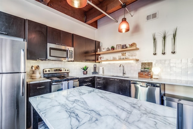 kitchen featuring light stone counters, sink, backsplash, appliances with stainless steel finishes, and dark brown cabinetry