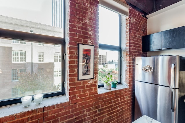 kitchen with stainless steel refrigerator and brick wall