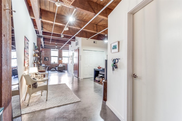 hall with brick wall, wood ceiling, and concrete flooring