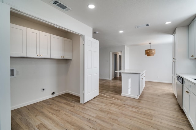 kitchen with light wood-type flooring, decorative light fixtures, white cabinetry, and stainless steel dishwasher