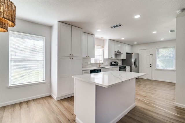 kitchen with white cabinets, a center island, light wood-type flooring, and appliances with stainless steel finishes