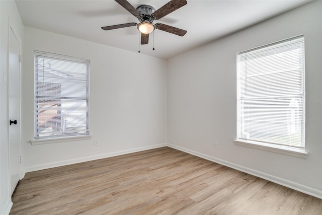 empty room featuring a wealth of natural light, ceiling fan, and light wood-type flooring