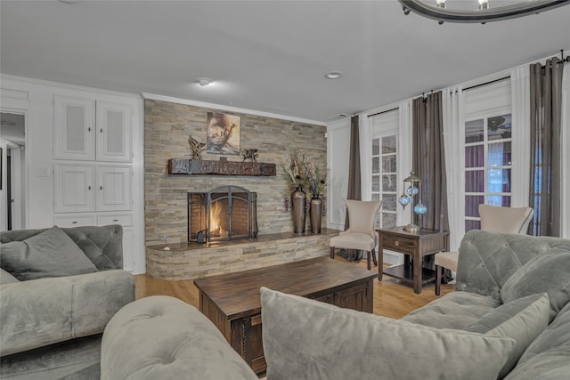 living room featuring a stone fireplace, crown molding, and light hardwood / wood-style floors