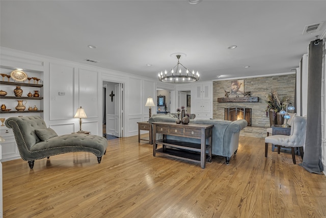 living room featuring a fireplace, light wood-type flooring, a chandelier, and ornamental molding