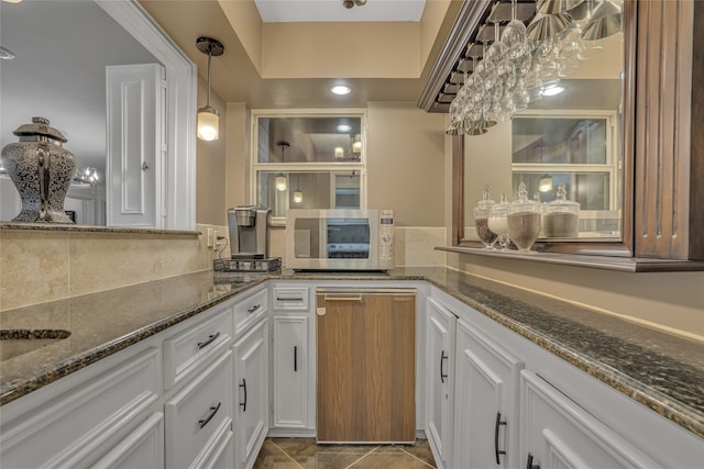 kitchen featuring white cabinets, pendant lighting, tile patterned flooring, and dark stone countertops