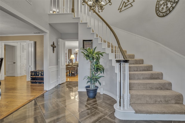 stairway with tile patterned floors, a chandelier, and ornamental molding