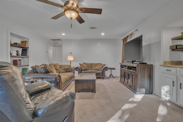 living room featuring ceiling fan, built in features, and light colored carpet