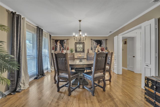 dining room featuring plenty of natural light, light wood-type flooring, crown molding, and a chandelier