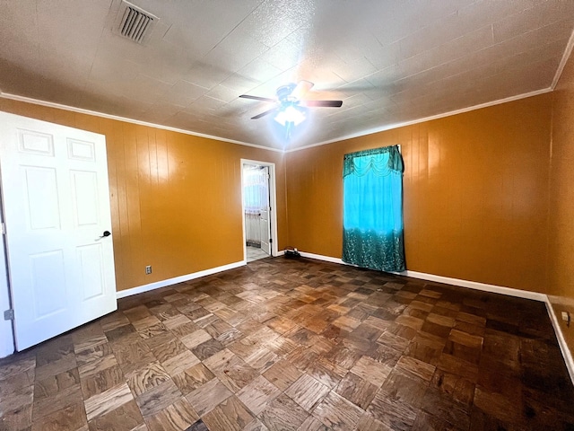 spare room featuring wooden walls, ceiling fan, and ornamental molding