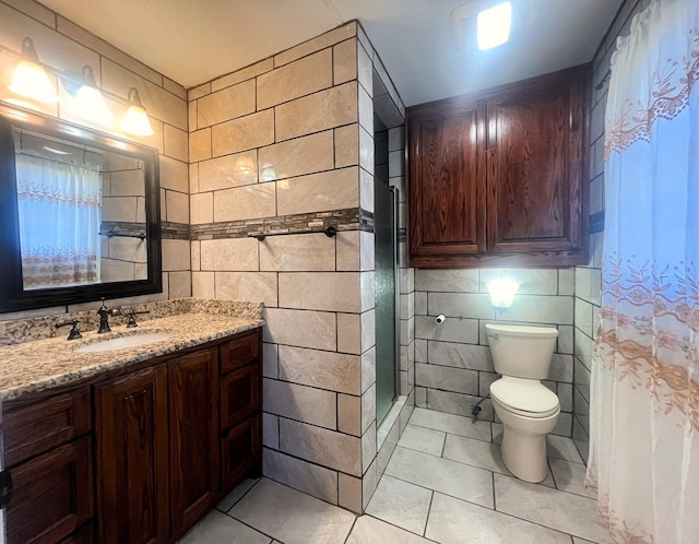 bathroom with tile patterned flooring, vanity, tile walls, and walk in shower