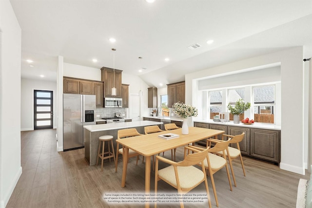 dining room featuring vaulted ceiling and light hardwood / wood-style floors