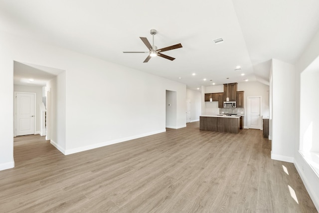 unfurnished living room with ceiling fan, light wood-type flooring, and vaulted ceiling