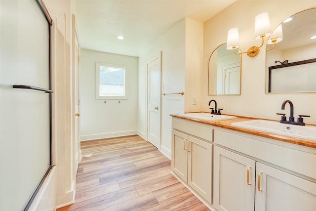 bathroom with wood-type flooring, vanity, and enclosed tub / shower combo