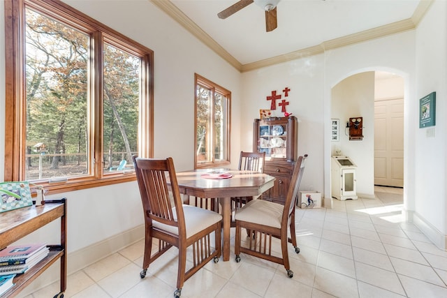 tiled dining space with ceiling fan and ornamental molding