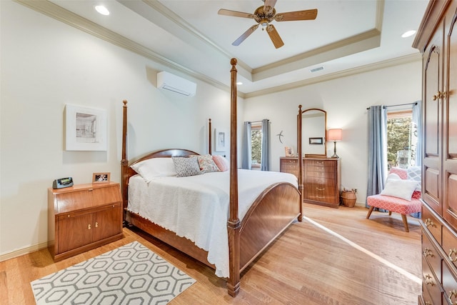 bedroom with crown molding, a tray ceiling, light hardwood / wood-style flooring, and a wall unit AC