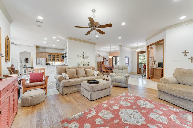 living room featuring ceiling fan, ornamental molding, and light hardwood / wood-style flooring