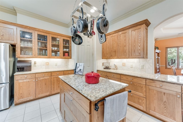 kitchen with stainless steel fridge, a center island, tasteful backsplash, and light stone counters