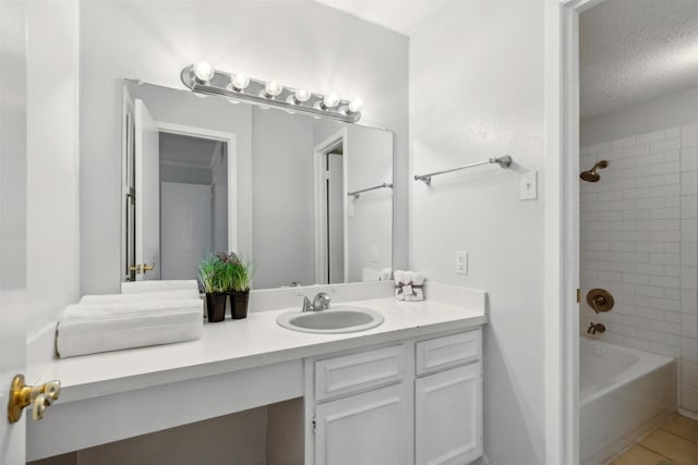 bathroom with vanity, a textured ceiling, tiled shower / bath, and tile patterned flooring