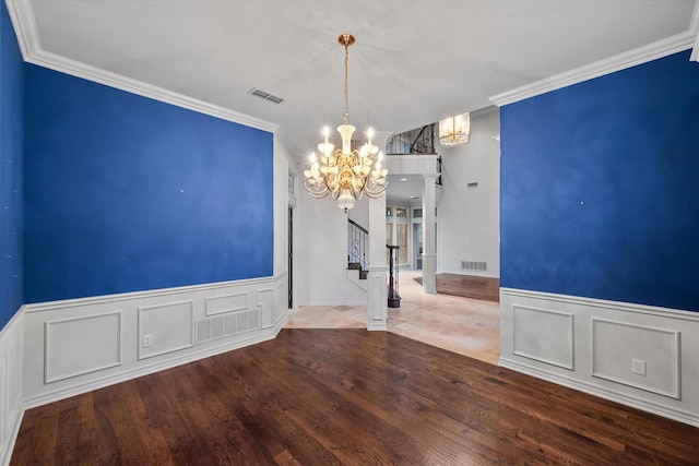 empty room with ornamental molding, hardwood / wood-style floors, and a notable chandelier