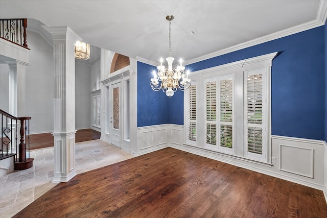 unfurnished dining area with a wainscoted wall, an inviting chandelier, and stairway