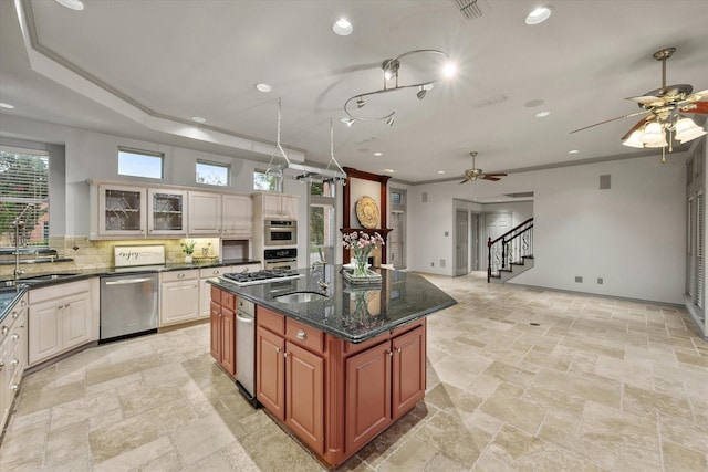 kitchen featuring stone tile flooring, a ceiling fan, decorative backsplash, and appliances with stainless steel finishes
